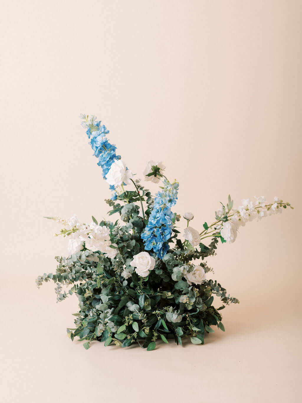 Vibrant floral arrangement with blue delphinium, white roses, and eucalyptus greens from The Aurora Full Collection.