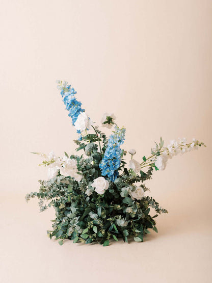 Vibrant floral arrangement with blue delphinium, white roses, and eucalyptus greens from The Aurora Full Collection.